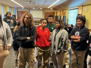 Group of students watch as mentor organizes data on the whiteboards